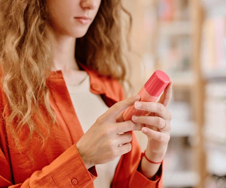 A woman displays a pink lipstick tube