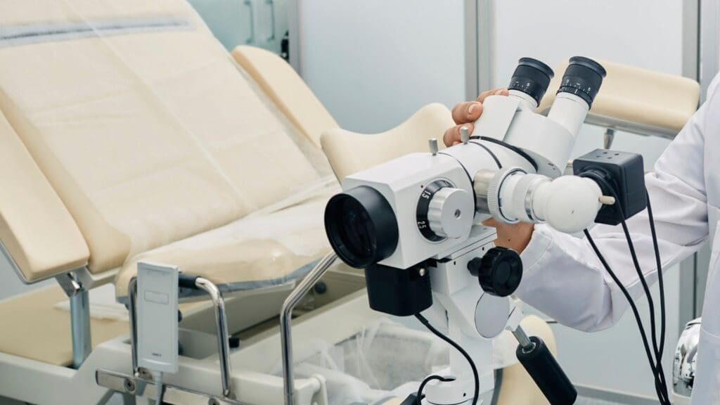Close-up of a gynecological examination chair and a colposcope used by a doctor for cervical examinations in a medical clinic.