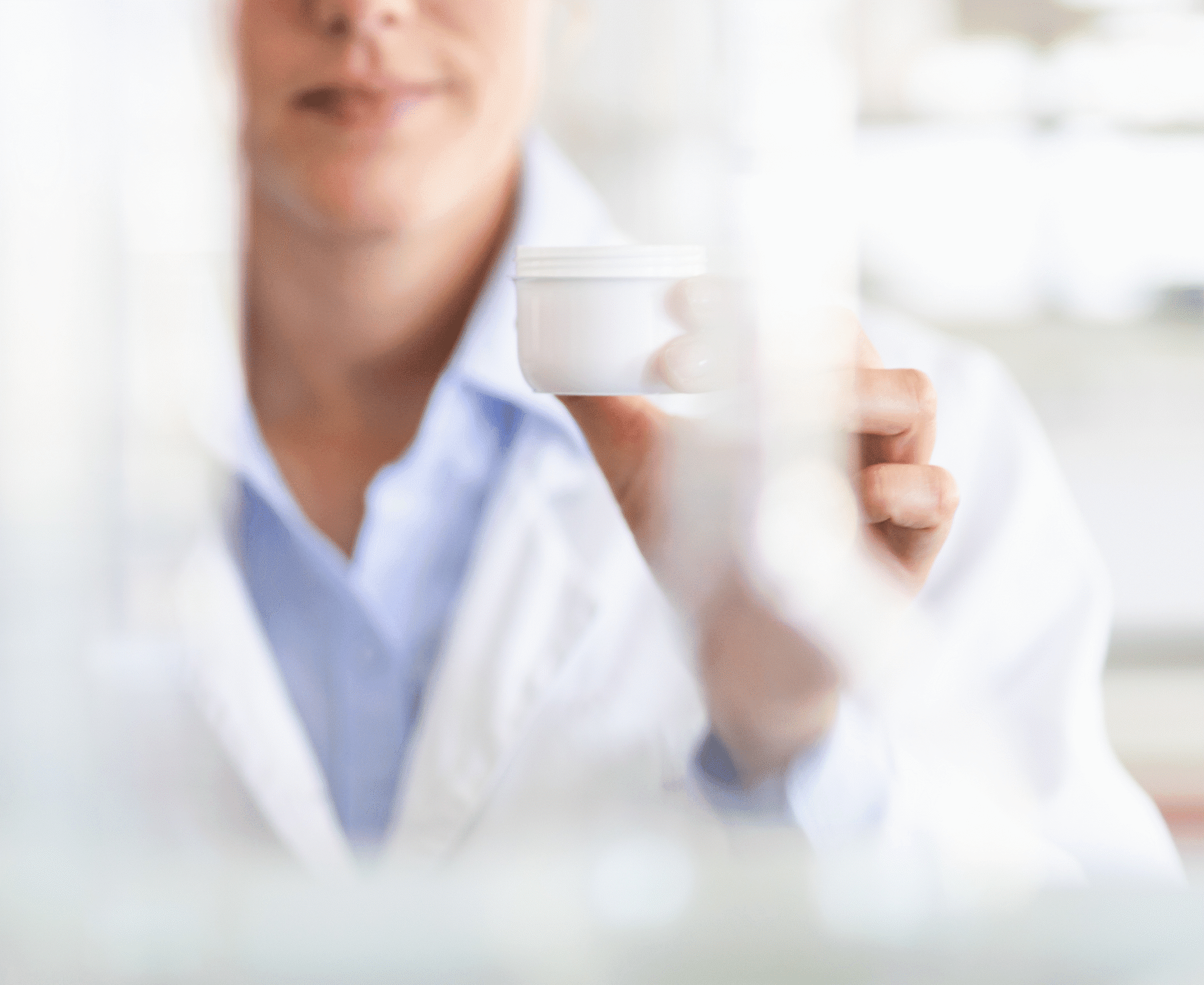 Laboratory professional examining a cosmetic cream container during product quality and safety testing.
