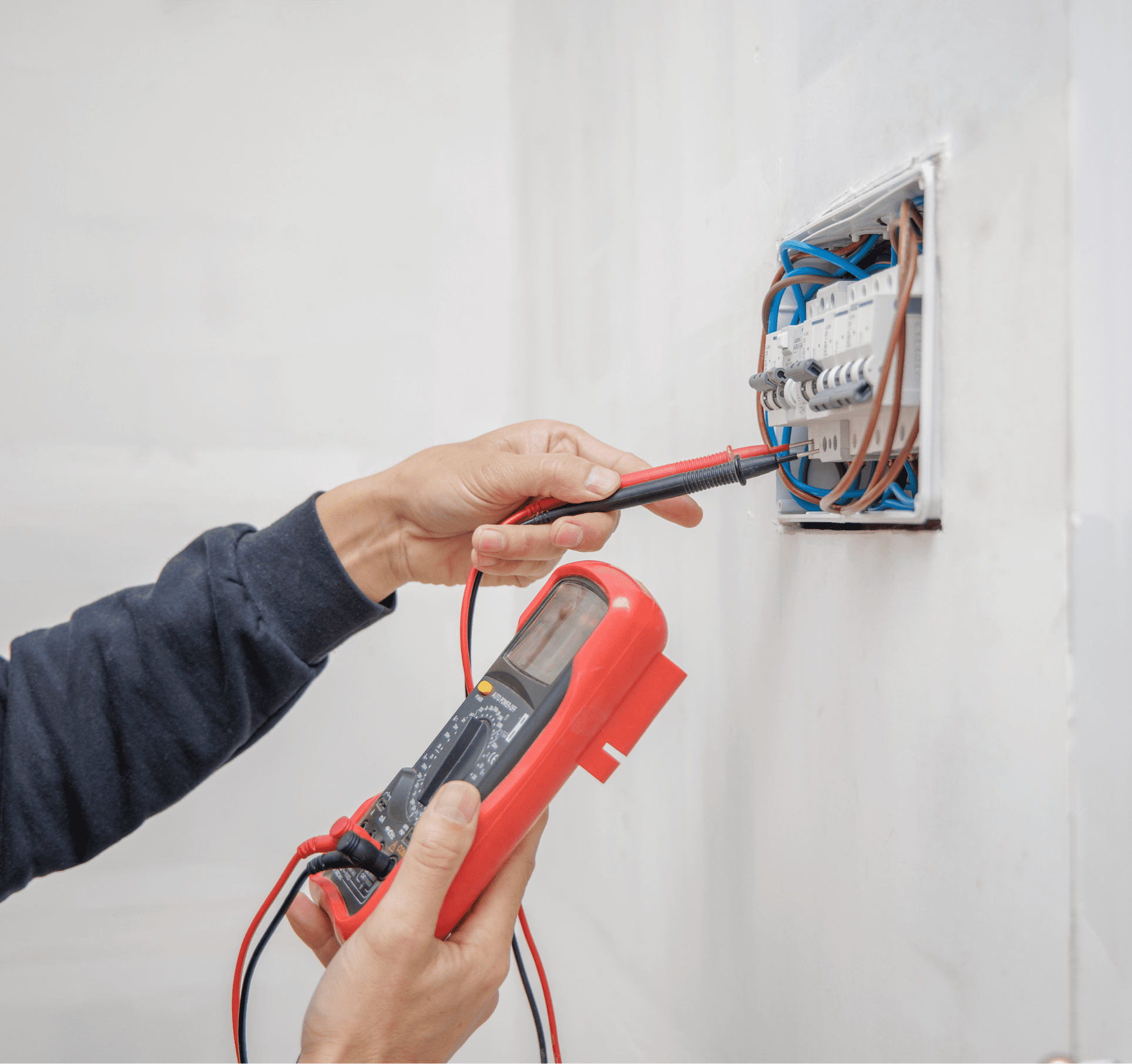 Technician using a multimeter to test an electrical circuit breaker panel.”
