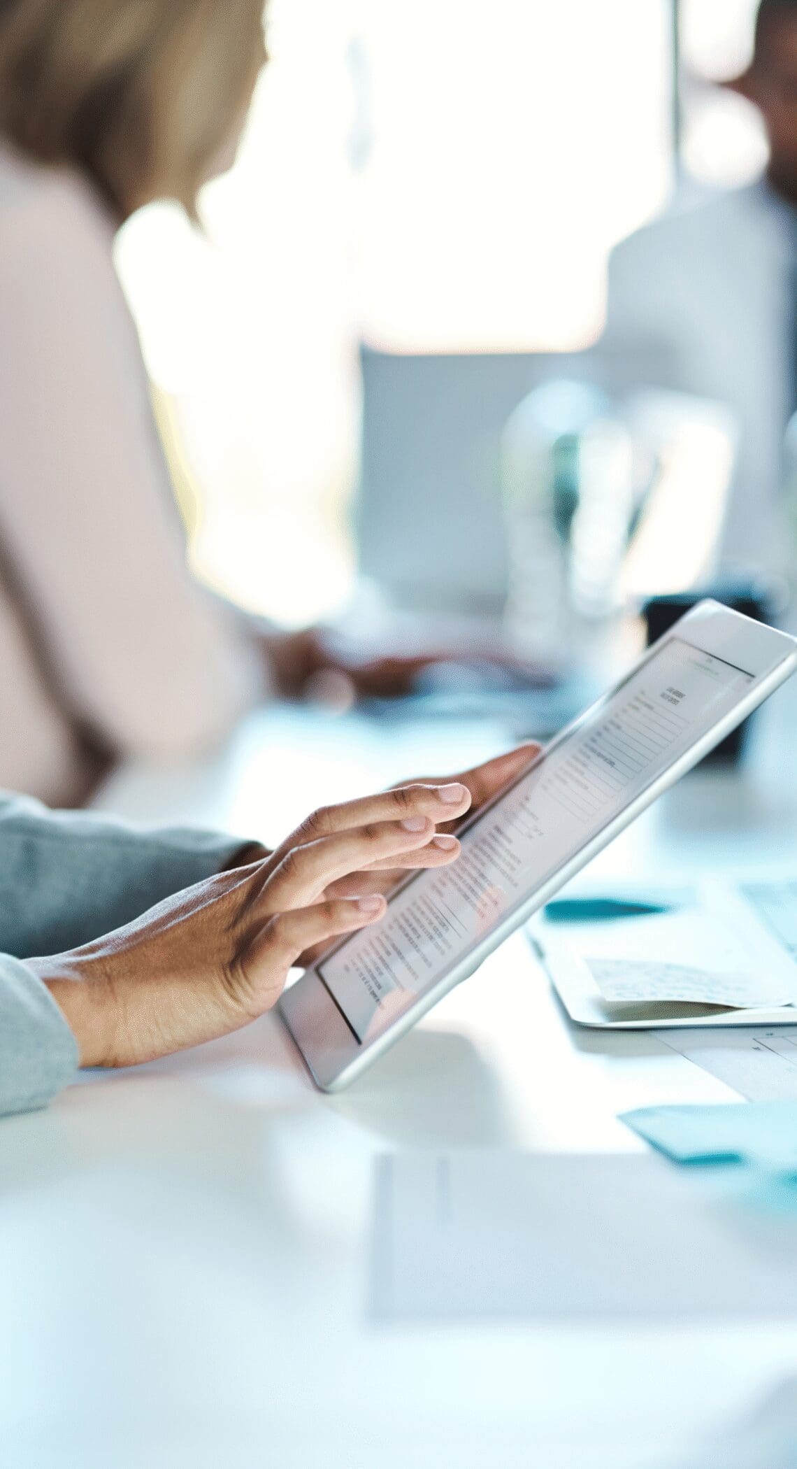 Business professional reviewing digital documents on a tablet during a meeting in a modern office.