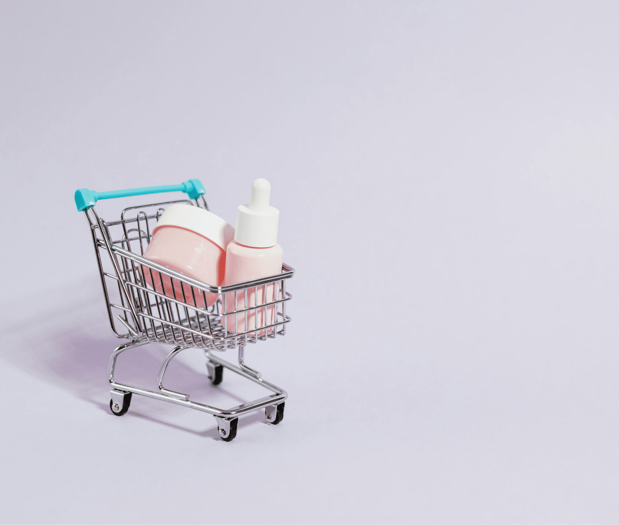 Skincare creams and serum in a small shopping cart representing beauty e-commerce and online cosmetic purchases.