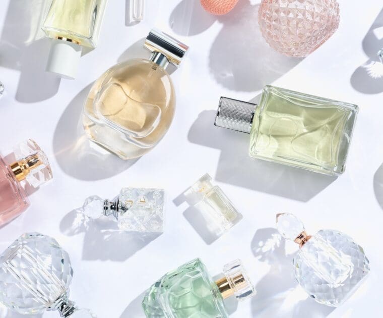 Group of elegant perfume bottles arranged together on a soft, neutral background with warm lighting.