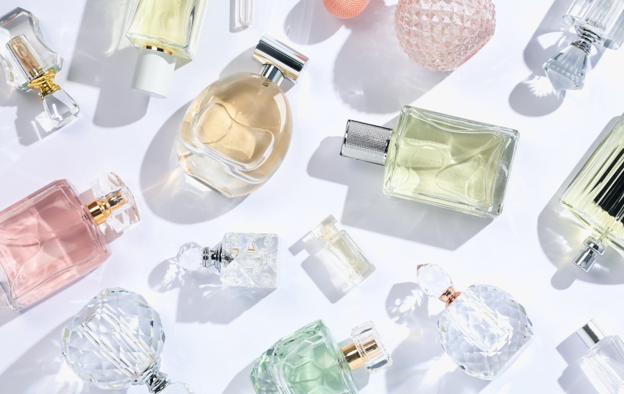 Group of elegant perfume bottles arranged together on a soft, neutral background with warm lighting.