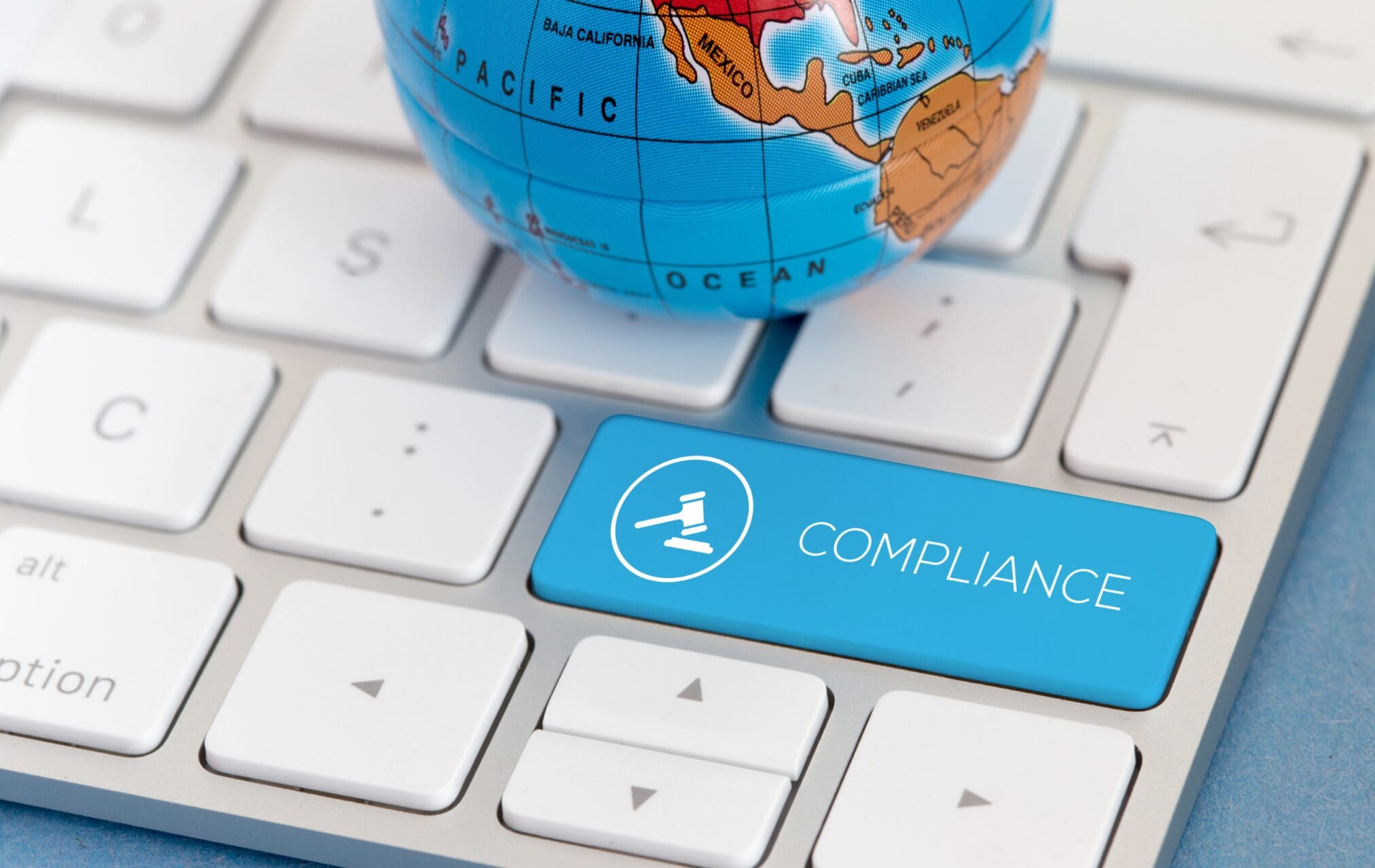 Global compliance concept with compliance key on keyboard and world globe.