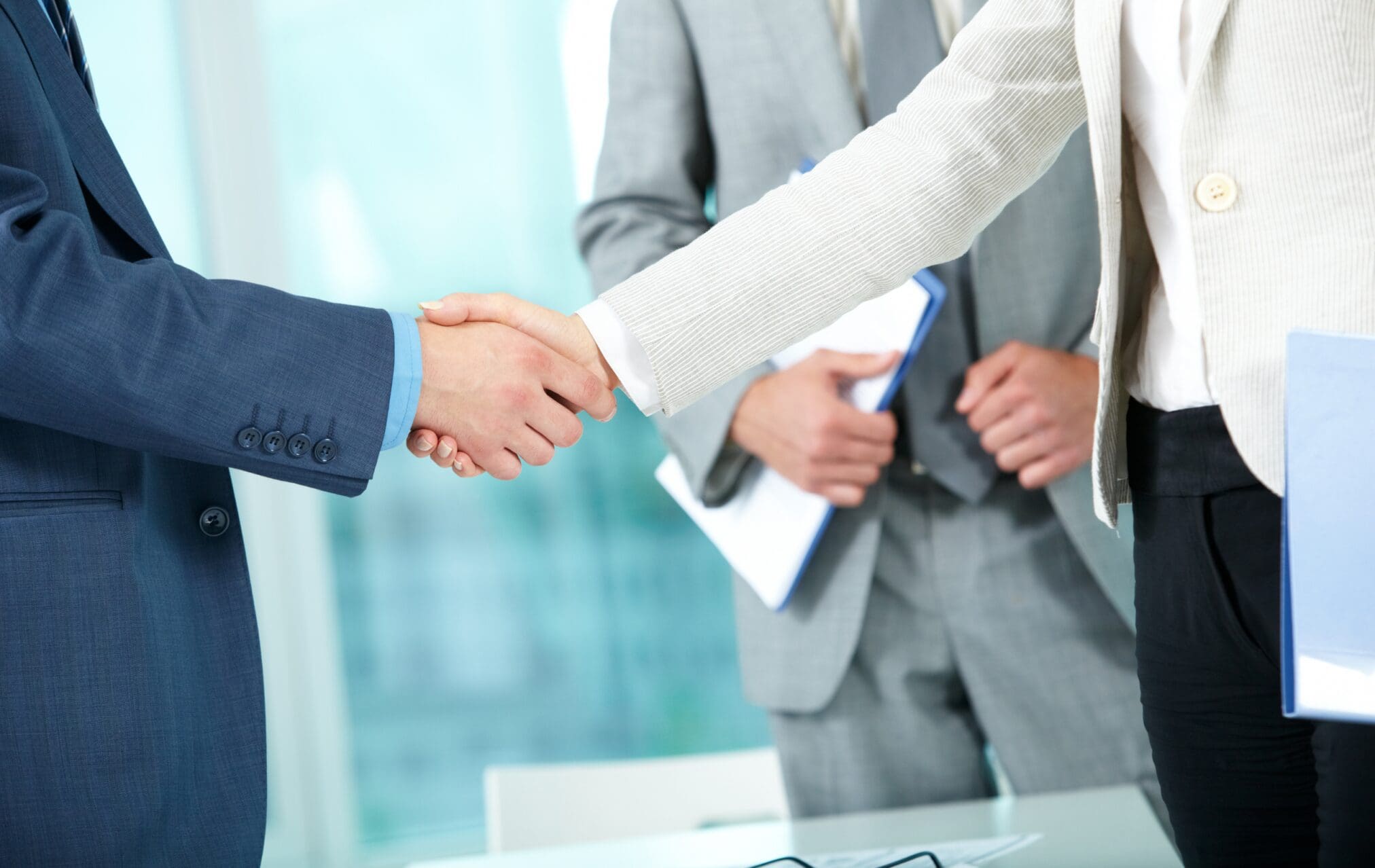 Business professionals shaking hands during a regulatory consulting and compliance partnership meeting.