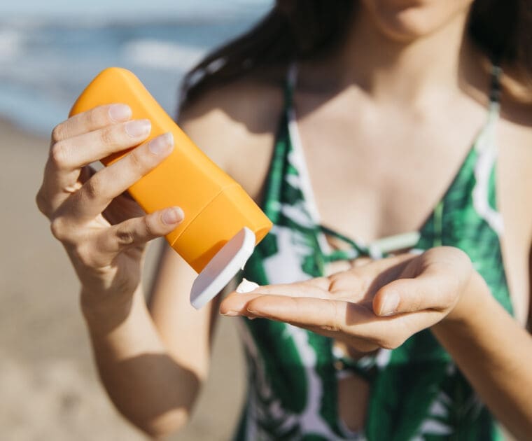 woman applying sunscreen at a beach